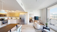 Located at 8075 NW 107th Ave in Doral, FL, this thoughtfully designed 2-bedroom, 1-bathroom residence offers a modern aesthetic throughout its single-floor layout. The open-concept living, dining, and kitchen area creates a seamless flow, bathed in natural light from large floor-to-ceiling windows that lead to a private balcony with outdoor views. Light wood-look flooring runs throughout, complementing the bright white walls and clean-lined design.

The kitchen features warm natural wood upper cabinetry, white lower cabinets, white countertops, stainless steel appliances including a French door refrigerator and dishwasher, and track lighting overhead. The adjacent dining area comfortably accommodates a full-sized table, while the living room provides a relaxed, open setting.

The primary bedroom is a well-appointed retreat featuring a geometric-patterned accent wall, a dedicated closet, and warm lighting. The second bedroom stands out with a bold tropical-print wallpapered accent wall, adding a vibrant, decorative touch. Both rooms are serviced by a clean, modern bathroom with large-format tile walls, a glass-enclosed walk-in shower, and mosaic tile flooring. Additional conveniences include in-unit laundry, two closets, and a dedicated entrance.