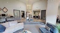 Located at 2713 N Collins St in Arlington, Texas, this single-story clubhouse presents a sophisticated, contemporary design highlighted by dramatic vaulted ceilings that create a grand sense of openness throughout the interior. The space is organized into distinct yet interconnected zones, beginning with a welcoming entry foyer anchored by a warm wood-and-glass front door, a decorative console table, and an oval mirror that sets an elegant tone upon arrival.

Moving inward, the main lounge area features a sunken carpeted seating zone furnished with curved sofas, tufted blue accent chairs, and a rounded coffee table—all arranged to encourage comfortable interaction. A raised hardwood platform transitions to the central reception area, where a metallic accent table with fresh floral arrangements serves as a focal point. The leasing desk area is situated beneath recessed lighting and decorated with metallic wall art and framed pieces.

A separate seating alcove at the rear of the space is enveloped by floor-to-ceiling windows and glass doors, providing panoramic views of an outdoor pool area complete with a stone fountain and lush landscaping. Track lighting and exposed beams accent the vaulted ceiling above. Additional private office spaces and utility areas branch off the main hall, completing this well-appointed community facility.