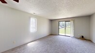 Located at 6747 W Par Ln in Wichita, Kansas, this single-floor, 2-bedroom, 2-bathroom home offers a practical and comfortable layout. The combined kitchen and living area serves as the heart of the home, with the living room featuring plush carpeting, a ceiling fan, a side window for natural light, and a sliding glass door that opens to a view of the surrounding greenery. A pass-through window connects the living room to the galley-style kitchen, which is outfitted with dark cabinetry, light wood-tone countertops, wood-look flooring, and black appliances including a refrigerator, microwave, and stove. Both bedrooms are carpeted and finished with neutral tones, each receiving natural light through windows fitted with blinds. The primary bedroom offers a generous footprint with ample wall space. Both bathrooms share a consistent design, featuring wood-look tile flooring, dark vanity cabinetry with light countertops, and a full tub-shower combo with a clean white surround. Textured ceilings are present throughout the home, adding a classic residential character. The overall layout is straightforward and efficiently organized, making good use of the available space.