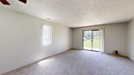 Located at 6747 W Par Ln in Wichita, Kansas, this single-floor, 2-bedroom, 2-bathroom home offers a practical and comfortable layout. The combined kitchen and living area serves as the heart of the home, with the living room featuring plush carpeting, a ceiling fan, a side window for natural light, and a sliding glass door that opens to a view of the surrounding greenery. A pass-through window connects the living room to the galley-style kitchen, which is outfitted with dark cabinetry, light wood-tone countertops, wood-look flooring, and black appliances including a refrigerator, microwave, and stove. Both bedrooms are carpeted and finished with neutral tones, each receiving natural light through windows fitted with blinds. The primary bedroom offers a generous footprint with ample wall space. Both bathrooms share a consistent design, featuring wood-look tile flooring, dark vanity cabinetry with light countertops, and a full tub-shower combo with a clean white surround. Textured ceilings are present throughout the home, adding a classic residential character. The overall layout is straightforward and efficiently organized, making good use of the available space.