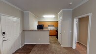 Located at 1601 Towne Crossing Blvd in Mansfield, Texas, this single-floor residence offers a well-organized layout with distinct living, kitchen, bedroom, and bathroom spaces. Crown molding runs throughout the main living and kitchen areas, adding a refined architectural detail to the interior.

The kitchen is a functional centerpiece of the space, featuring warm honey-toned cabinetry extending to the ceiling with ample upper and lower storage. Granite-style countertops provide a durable work surface, complemented by a double-basin sink, black appliances including a full-size refrigerator, dishwasher, and range, and wood-look flooring for easy maintenance. A breakfast bar separates the kitchen from the adjacent living area, which transitions to plush carpeting ideal for comfort underfoot.

The living area benefits from natural light through blinds-fitted windows and is finished with the same crown molding detail seen throughout. The bedroom is a spacious, quiet retreat with soft carpet, a ceiling light fixture, and a window that allows natural light to filter in.

The bathroom is well-appointed with a granite-style vanity countertop, rich wood-toned cabinetry, a large mirror with overhead lighting, a toilet, and a full tub-shower combination. Wood-look flooring extends through the bathroom, tying together the overall aesthetic of the residence.