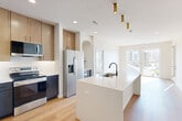Located in Elkhorn, Nebraska, this thoughtfully designed 2-bedroom, 2-bathroom residence offers a clean, contemporary aesthetic throughout its single-floor layout. The open-concept kitchen serves as the heart of the home, showcasing a generous white quartz island with a matte black faucet and sink, two-tone cabinetry combining navy and warm wood tones, stainless steel appliances, and gold pendant lighting. The kitchen flows seamlessly into the living area, which benefits from large sliding doors that invite abundant natural light and connect the interior to outdoor views. Both bedrooms are carpeted and bright, each featuring wide windows with views of the surrounding neighborhood and ceiling fans for year-round comfort. The primary bedroom is a well-proportioned retreat with access to a dedicated bathroom, complete with a dark-cabinetry vanity, a backlit mirror, and hardwood-style flooring. A walk-in closet with built-in shelving provides ample storage. The second bathroom mirrors the same modern design language, featuring a tub-shower combo with sleek black hardware and a matching vanity. Crisp white walls and light wood-tone flooring in the common areas create a cohesive, airy ambiance throughout this well-appointed Elkhorn residence.