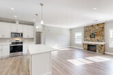 This well-appointed 2-bedroom, 2-bathroom residence in Chelmsford, MA offers a thoughtfully designed single-floor layout with modern finishes throughout. The open-concept kitchen and living area serves as the heart of the home, anchored by a striking floor-to-ceiling natural stone fireplace that adds warmth and character to the living room. Large windows allow abundant natural light to fill the space, highlighting the light-toned hardwood-style flooring that runs seamlessly throughout. The kitchen is equipped with crisp white shaker cabinetry, quartz countertops, stainless steel appliances, a deep single-basin sink, and a generous central island with pendant lighting — ideal for both cooking and casual dining. The primary bedroom is a spacious retreat featuring recessed lighting, crown molding, and a well-sized double closet. The second bedroom also offers ample space, natural light, and crown molding details. Both bathrooms are finished with white vanities, quartz countertops, and clean, contemporary fixtures; one features a walk-in glass shower. Additional conveniences include a dedicated laundry room and five closets providing excellent storage. Recessed lighting, crown molding, and a neutral gray palette create a cohesive and refined aesthetic throughout the entire home.