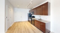 Located at 2615 Bladensburg Rd NE in Washington, DC, this one-bedroom, one-bathroom unit offers a well-designed layout that maximizes every square foot. The open-concept living and kitchen area is anchored by light hardwood-style flooring that runs throughout, creating a clean, cohesive look. A large window at the far end of the living space floods the area with natural light and provides views of the surrounding neighborhood.

The kitchen is outfitted with rich dark-wood cabinetry extending to the ceiling for ample storage, granite countertops, a stainless steel sink, and a full suite of black appliances including a refrigerator, electric range, built-in microwave, and dishwasher. Track lighting overhead adds both functionality and a modern touch.

The bedroom is carpeted for comfort and features its own window with natural light, along with access to a dedicated walk-in closet complete with wire shelving. The full bathroom includes tile flooring, a soaking tub with a tiled surround and shower, and a clean, functional layout. The unit is completed by a private entry door, making it a self-contained and practical living space in Northeast Washington, DC.