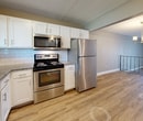 This 930-square-foot, single-floor apartment at 401 Rosery Rd NE, Apt 104 in Largo, Florida offers 2 bedrooms and 2 bathrooms with a practical, well-appointed layout. The open living and dining area features warm wood-look vinyl flooring, neutral taupe walls, white baseboards, and a textured ceiling, with an elegant chandelier adding a refined touch. A wrought iron railing defines the stairwell area, contributing a classic architectural detail to the open space. The kitchen is thoughtfully designed with white shaker cabinetry, granite countertops, white subway tile backsplash, a stainless steel appliance suite including a dishwasher, range, and microwave, and a window above the sink that brings in natural light. Both bedrooms are carpeted and feature neutral tones, windows for natural light, and closets with built-in rods. The primary bedroom measures 170 square feet and includes direct access to a private bathroom featuring a granite-topped vanity and wood-look flooring. The additional bathroom includes a walk-in shower with white subway tile walls, a mosaic tile floor, and brushed nickel fixtures. A hallway connects the unit's two closets and both bathrooms, completing this efficiently designed apartment.