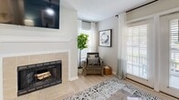 Located in Morrisville, NC, this thoughtfully designed 2-bedroom, 2-bathroom single-floor residence offers a comfortable and modern living experience. The open-concept layout connects the kitchen, dining, and living areas seamlessly. The kitchen is a standout, featuring a large center island with marble-look countertops, white cabinetry, stainless steel appliances, and light wood-style flooring that carries throughout the main living spaces. The dining area accommodates a cozy table setting, while the living room impresses with a tile-surround fireplace, multiple windows that invite abundant natural light, and access to the outdoors via glass doors. The primary bedroom features a ceiling fan, plush carpeting, a warm accent wall, and a private en-suite bathroom. The second bedroom is equally comfortable, with carpet, a ceiling fan, and a large window. Both bathrooms are finished with elegant marble-top vanities and white cabinetry with brushed nickel hardware. The in-unit laundry area includes a full-size washer and dryer with built-in shelving. Two closets and a dedicated laundry room add practical storage throughout this well-rounded residence.