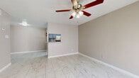 Located at 8323 Cinnamon Ln in Houston, TX, this single-story, 3-bedroom, 1-bathroom home offers a practical and well-organized layout finished consistently in light ceramic tile flooring throughout every room. The combined living and dining area is bright and open, featuring a ceiling fan with light fixture and a pass-through window connecting directly to the kitchen, enhancing the sense of connectivity between spaces. Natural light filters in through a window, adding warmth to the neutral-toned walls. The galley-style kitchen is efficiently designed with cabinetry on both sides, black appliances including a refrigerator, dishwasher, and range, a tile backsplash, and light stone countertops — providing ample workspace and storage. Three bedrooms offer comfortable accommodations, each with tile flooring, ceiling-mounted ventilation, and closet access; the spacious primary bedroom includes a dedicated closet. The full bathroom is appointed with full-height tile surrounding a soaking tub and shower combination, accented by a decorative mosaic niche. A dedicated laundry room with hook-ups adds everyday convenience. Three closets are distributed throughout the home, maximizing storage options across the floor plan.