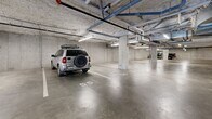 Located at 728 Meaford Ave in Langford, British Columbia, this large-scale underground parking facility offers a well-organized and functional space designed to accommodate a significant number of vehicles. The parkade spans a single level of considerable size, with a smooth poured-concrete floor, clearly painted stall markings, and numbered parking bays — including designated small car spaces — to ensure efficient use of the available area.

The structure features exposed concrete ceilings, walls, and support columns throughout, giving the facility a utilitarian yet solid character. Overhead, a network of mechanical piping, conduit, and fire suppression systems runs across the ceiling, all illuminated by evenly spaced fluorescent strip lighting that ensures consistent visibility throughout the space.

A notable feature of this parkade is the availability of electric vehicle (EV) charging stations, with multiple wall-mounted charging units visible along one section of the facility — a modern amenity reflecting contemporary infrastructure standards. Additionally, a dedicated bicycle storage area is integrated into the parkade, equipped with wall-mounted and freestanding bike racks capable of accommodating numerous bicycles. Stairwell access doors are positioned at key points throughout the facility, providing convenient entry and exit to the building above.