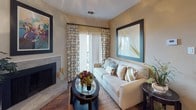 This one-bedroom, one-bathroom unit with a den is thoughtfully laid out across a single floor, offering a comfortable and functional living experience. The living room serves as the heart of the home, featuring a stone-surround fireplace as a focal point, wood-style flooring, and a sliding glass door that welcomes natural light while providing outdoor access. Patterned drapery and neutral wall tones give the space a warm, inviting ambiance.

The kitchen is well-appointed with dark cabinetry, granite-style countertops, a tile backsplash, and black appliances including an electric range and built-in microwave. A doorway off the kitchen leads directly to a dedicated laundry area with a full-size washer and dryer, adding everyday convenience.

The bedroom is generously sized, featuring plush carpet, a large window with blinds and decorative curtains, and ample room for full-size furniture. A textured ceiling and soft neutral tones carry throughout. The bathroom includes a granite-style vanity countertop, undermount sink, hardwood-style flooring, and a tub-shower combination. The additional den provides flexible space ideal for a home office or guest area.