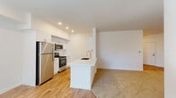 This well-appointed single-floor residence offers a clean, modern aesthetic throughout, combining functional design with contemporary finishes. The open-concept kitchen and living area serves as the heart of the home, anchored by a central island with a built-in sink and white countertops. The kitchen is equipped with stainless steel appliances — including a refrigerator, range, and microwave — paired with crisp white shaker-style cabinetry and light hardwood flooring. Recessed lighting brightens the space, which flows seamlessly into a generously sized carpeted living area.

Two well-sized bedrooms each feature plush wall-to-wall carpeting and built-in closets offering ample storage. Natural light filters in through windows, lending each room a bright and airy feel. The two bathrooms are finished with warm stone-look tile flooring, white vanities with shaker-style cabinetry, and brushed nickel fixtures. One bathroom includes a full tub-and-shower combination, while the second offers a clean, functional layout.

A dedicated laundry area rounds out the space, complete with white upper and lower cabinetry, a countertop workspace, and a utility sink — providing practical convenience. The overall palette of white walls, light flooring, and neutral tones creates a cohesive and inviting atmosphere throughout.
