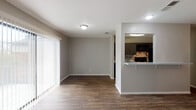 Located at 8000 Midcrown Dr, Unit 706, in San Antonio, TX, this single-floor residence offers a well-organized layout with a blend of practical finishes throughout. The open-concept living area is finished with warm wood-look flooring and neutral gray walls, creating a clean, versatile backdrop. Large vertical blinds along a floor-to-ceiling sliding window wall allow natural light to fill the space while providing privacy. A built-in pass-through counter connects the living area to the kitchen, offering a convenient bar-style ledge that enhances the open flow between spaces. The kitchen is well-appointed with dark gray cabinetry, a mosaic tile backsplash, light speckled countertops, a stainless steel sink, and a full suite of black appliances including a refrigerator, electric range, microwave, and dishwasher. A wall-mounted shelf in the hallway area adds a decorative display element. The bedrooms feature plush carpeting and horizontal windows that bring in soft natural light while maintaining an elevated sense of privacy. The bathroom includes wood-look flooring, a full-size soaking tub with shower, and clean white fixtures throughout. The overall design is cohesive and move-in ready, with consistent finishes across every room.