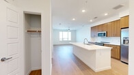 This thoughtfully designed one-bedroom, one-bathroom residence in Centennial, Colorado offers a well-appointed layout with contemporary finishes throughout. Light wood-tone flooring runs continuously across the open-concept living space, creating a warm, cohesive aesthetic.

The kitchen is a standout feature, showcasing warm wood cabinetry that extends to the ceiling for ample storage, white subway tile backsplash, stainless steel appliances including a refrigerator with ice maker, oven, microwave, and dishwasher, and a central island with a white quartz countertop and undermount sink. A built-in entryway nook with cabinetry, hooks, and a bench provides a convenient drop zone near the entry.

The living area is bright and airy, with recessed lighting, a ceiling fan, and large windows that frame sweeping views of the surrounding cityscape. The bedroom is comfortably sized with large windows and a glass door offering additional outdoor views and abundant natural light.

The bathroom features a wide wood-toned vanity with quartz countertop, a large wall mirror, and clean tile flooring. An in-unit laundry area accommodates a full-size side-by-side washer and dryer. A dedicated closet and additional storage complete this well-organized, modern residence.
