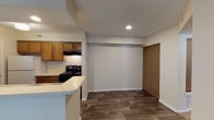 Located at 1956 Chimney Ln in Kettering, Ohio, this single-floor residence offers a functional and well-organized layout designed for comfortable everyday living. The kitchen is a standout feature, equipped with warm oak cabinetry, light countertops, a double-basin sink, a black gas range, a dishwasher, and a full-size refrigerator. A peninsula counter seamlessly connects the kitchen to the adjacent living area, creating an open and accessible flow between spaces. Wood-look plank flooring runs throughout the kitchen and main living areas, providing a durable and cohesive aesthetic. The living area is enhanced by a fireplace, adding a welcoming focal point to the space. Multiple bedrooms are finished with soft wall-to-wall carpeting and feature windows that allow natural light and views of the surrounding greenery. The bathroom is appointed with a warm wood vanity, light countertop, a large mirror with overhead lighting, and matching wood-look flooring. Neutral wall tones and textured ceilings are consistent throughout the home, contributing to a clean and understated interior. The layout, as seen in the dollhouse view, provides a logical and connected flow from the entryway through the living, kitchen, and private bedroom areas.