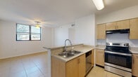 Located in Miami, FL, this single-floor, 2-bedroom, 2-bathroom residence offers a practical and well-organized layout. The open-concept kitchen serves as the heart of the home, featuring light wood cabinetry, stainless steel appliances including a refrigerator and electric range, a double-basin sink, and speckled granite-style countertops that extend to a peninsula island — ideal for casual dining or meal prep. The kitchen flows naturally into the combined dining and living area, which benefits from a ceiling fan and a window that brings in natural light.

The hallway connects the living spaces to the bedrooms and bathrooms, aided by ample closet storage — six closets in total — along with a dedicated pantry and in-unit laundry. The primary bedroom offers a comfortable footprint with ceiling fan and natural light. The secondary bedroom features corner windows that frame views of the surrounding Miami neighborhood and palm-lined streetscapes, filling the room with abundant daylight.

Both bathrooms are finished consistently with speckled countertop vanities and wood cabinetry, with one bathroom featuring a full tub-shower combination with white tile surround. Light tile flooring runs throughout the unit, creating a clean, cohesive aesthetic well-suited to the Miami climate.