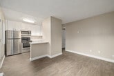 This well-appointed one-bedroom, one-bathroom unit offers a thoughtfully designed single-floor layout that maximizes every square foot of its compact footprint. The kitchen stands out as a key feature, showcasing crisp white shaker-style cabinetry, stainless steel appliances including a refrigerator, electric range, and over-the-range microwave, as well as a granite-style countertop that extends into a peninsula breakfast bar — ideal for casual dining or additional prep space. Light wood-look flooring runs through the kitchen and living areas, contributing to a clean, cohesive aesthetic. The living room is bright and open, featuring a window with vertical blinds that allows natural light and outdoor views of surrounding greenery. A wall-mounted air conditioning unit provides climate control. The bedroom is a comfortable size, also featuring wood-look flooring, warm neutral walls, a textured ceiling, and a window that brings in additional natural light. The bathroom includes a full tub and shower combination with brushed nickel fixtures and white cabinetry. A dedicated closet provides practical storage. Throughout the unit, consistent neutral tones and modern finishes create a clean, move-in-ready ambiance.