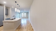 Located at 750 W Grand Pkwy S in Katy, TX, this thoughtfully designed one-bedroom, one-bathroom unit offers a well-appointed single-floor layout with modern finishes throughout. The open-concept living and kitchen area is anchored by light hardwood-style flooring that flows seamlessly through the main spaces. The kitchen is a standout feature, equipped with gray shaker-style cabinetry, white quartz countertops, a large center island with an undermount sink and matte black faucet, stainless steel appliances including a refrigerator, range, microwave, and dishwasher, and a white subway tile backsplash. Elegant pendant lighting hangs above the island, adding a modern touch. The living room receives ample natural light through multiple windows with blinds and includes a ceiling fan for added comfort, along with direct access to an exterior door. The bedroom offers plush carpeting, a ceiling fan, a window with neighborhood views, and a dedicated closet. The bathroom is well-finished with gray cabinetry, a white quartz vanity, a large mirror, matte black fixtures, and a glass-enclosed shower with marble-style tile surround. Clean neutral tones and recessed lighting contribute to a bright, contemporary ambiance throughout the unit.