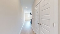 Located at 1450 Peachtree Industrial Blvd in Sugar Hill, GA, this one-bedroom, one-bathroom residence offers a thoughtfully designed single-level layout with modern finishes throughout. A bright, open hallway with light wood-style flooring and recessed lighting leads into the main living and kitchen area. The kitchen is a standout feature, boasting white shaker cabinetry with matte black hardware, granite countertops, a bold navy blue center island topped with matching granite, and a full suite of stainless steel appliances including a refrigerator with ice maker, electric range, and microwave. Two industrial-style pendant lights add a contemporary touch overhead. The bedroom offers plush carpeting, a ceiling fan, and a double window that allows natural light to fill the room. An adjoining walk-in closet provides ample storage with wire shelving systems on multiple walls and soft carpet underfoot. The bathroom is clean and functional, featuring wood-look tile flooring, white subway tile in the shower stall, a granite-topped vanity with white cabinetry, and brushed nickel fixtures throughout. The overall aesthetic is modern and cohesive, with a neutral palette that creates a bright, welcoming ambiance.