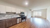 Located at 1519 82nd St in Victoria, MN, this two-bedroom, two-bathroom unit offers a well-designed single-level layout with a clean, modern aesthetic. The open-concept kitchen and living area serves as the heart of the home, featuring warm hardwood-style flooring that flows seamlessly throughout. The kitchen is equipped with a full suite of stainless steel appliances—including a French door refrigerator with ice maker, gas range, built-in microwave, and dishwasher—complemented by two-tone cabinetry with crisp white upper cabinets and rich dark lower cabinets, granite-look countertops, and a textured tile backsplash. The living area benefits from multiple windows that invite abundant natural light and provides access to an outdoor balcony area. Both bedrooms are carpeted in a neutral tone, offering a comfortable and quiet retreat. The primary bedroom is a well-proportioned space with room for a full furniture arrangement. The two bathrooms are finished with tile flooring and dark wood vanity cabinetry, each featuring a walk-in shower with grab bars—lending a practical, accessible design. A hallway and closet complete the layout, ensuring efficient use of every square foot in this thoughtfully appointed Victoria residence.