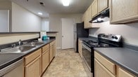 Located at 1200 Virginia Center Pkwy in Glen Allen, Virginia, this single-floor unit offers a well-organized layout designed for comfortable everyday living. The expansive living area is finished with neutral-toned carpet and features a ceiling fan, providing a bright and open atmosphere with easy flow into the kitchen and adjacent spaces. The galley-style kitchen is equipped with light wood cabinetry, dark countertops, tile flooring, and black appliances including a range and refrigerator. A peninsula breakfast bar connects the kitchen to the living area, making it ideal for casual dining or entertaining. The bedrooms are generously proportioned, each featuring soft carpeting, ceiling fans, and windows dressed with horizontal blinds that allow natural light while maintaining privacy. One bedroom includes a closet with built-in wire shelving, offering practical and organized storage. Both bathrooms are finished with tile flooring, a vanity with wood cabinetry and dark countertops, and a tub-shower combination with white tile surround and a curved curtain rod. Clean, neutral wall tones and white trim throughout the unit create a cohesive and move-in ready aesthetic.