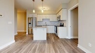 The Oakridge Suite is a well-appointed 2-bedroom, 1-bathroom residence located in London, Ontario, offering a thoughtfully designed layout across a single floor. The open-concept kitchen serves as a central highlight, featuring crisp white cabinetry, a classic subway tile backsplash, quartz countertops, a central island, stainless steel appliances, and elegant pendant lighting — making it both functional and visually appealing. The kitchen flows seamlessly into the living area, creating a cohesive and social living space. Luxury vinyl plank flooring in a warm grey-wood tone extends throughout the unit, lending a clean, contemporary feel. Both bedrooms are bright and well-proportioned, with warm neutral walls and large floor-to-ceiling windows that invite natural light and offer views of the surrounding London cityscape. The primary bedroom is a comfortable size, while the second bedroom also benefits from natural light via its own window. The bathroom is finished with elegant marble-style tile surrounding a soaker tub and shower combination, complemented by polished chrome fixtures. A dedicated closet provides practical storage. The suite's modern palette of neutral tones, quality finishes, and city-view windows create a refined and inviting urban living environment.