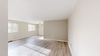 This single-floor, 2-bedroom, 1-bathroom residence offers a thoughtfully laid-out living space with a clean, modern aesthetic. The open living area is finished with light-toned hardwood flooring and neutral warm-beige walls, creating a bright and airy atmosphere. Multiple windows fitted with horizontal blinds allow generous natural light to fill the space, while ceiling fans in the living area and bedrooms provide year-round comfort.

The galley-style kitchen is well-appointed with modern taupe cabinetry, granite-look countertops, a classic white subway tile backsplash, and stainless steel appliances including a refrigerator, dishwasher, gas range, and over-the-range microwave. It connects seamlessly to the main living area, making the layout practical and functional.

The generously sized primary bedroom is carpeted for comfort and includes a ceiling fan, providing a cozy retreat. The second bedroom also features plush carpeting and a wall-mounted HVAC unit beneath a large window. Two closets provide ample storage throughout the unit.

The bathroom is finished with clean white tile in the tub/shower surround, a single-sink vanity with modern brushed nickel fixtures, and a round mirror, offering a simple and functional design. Overall, the space presents a move-in-ready environment with cohesive, contemporary finishes.