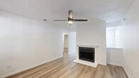 Located at 5451 Independence Pkwy in Plano, TX, this 2-bedroom, 2-bathroom single-story home offers a clean, modern aesthetic throughout. Light-toned wood-look flooring flows seamlessly across every room, creating a cohesive and inviting atmosphere. The living room serves as the heart of the home, featuring a classic fireplace with a white surround and a ceiling fan, making it a comfortable gathering space. Large windows along the front allow natural light to fill the area. The kitchen has been thoughtfully updated with white shaker cabinetry, granite countertops, an undermount sink, and stainless steel appliances including a refrigerator and dishwasher. The spacious primary bedroom provides ample room and is equipped with a ceiling fan, with direct access to a well-appointed bathroom featuring granite-topped vanity cabinetry. The second bedroom also includes a ceiling fan and a window with exterior views, offering a bright and airy feel. Both bathrooms are finished in a clean white palette, with one featuring a full tub-shower combination. Throughout the home, black hardware accents add a contemporary touch against the crisp white walls and trim, lending the space a fresh, move-in-ready character.