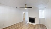 Located at 5451 Independence Pkwy in Plano, TX, this 2-bedroom, 2-bathroom single-story home offers a clean, modern aesthetic throughout. Light-toned wood-look flooring flows seamlessly across every room, creating a cohesive and inviting atmosphere. The living room serves as the heart of the home, featuring a classic fireplace with a white surround and a ceiling fan, making it a comfortable gathering space. Large windows along the front allow natural light to fill the area. The kitchen has been thoughtfully updated with white shaker cabinetry, granite countertops, an undermount sink, and stainless steel appliances including a refrigerator and dishwasher. The spacious primary bedroom provides ample room and is equipped with a ceiling fan, with direct access to a well-appointed bathroom featuring granite-topped vanity cabinetry. The second bedroom also includes a ceiling fan and a window with exterior views, offering a bright and airy feel. Both bathrooms are finished in a clean white palette, with one featuring a full tub-shower combination. Throughout the home, black hardware accents add a contemporary touch against the crisp white walls and trim, lending the space a fresh, move-in-ready character.