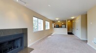 This single-floor residence offers a thoughtfully designed layout that balances open communal spaces with comfortable private quarters. The expansive living room is a standout feature, highlighted by a sleek granite-surround fireplace, soft wall-to-wall carpeting, and an abundance of natural light streaming through multiple large windows. A sliding glass door opens to a balcony, extending the living space outdoors and providing pleasant views of the surrounding greenery.

The kitchen is positioned adjacent to the living area and is defined by a raised breakfast bar that serves as both a functional workspace and a natural divider between the two spaces. Light maple cabinetry pairs cleanly with dark granite countertops, while stainless steel appliances — including a refrigerator, electric range, and over-the-range microwave — add a modern, polished finish. Pendant lighting overhead completes the kitchen's warm, inviting atmosphere.

The bedrooms are carpeted and bathed in natural light through generous windows that frame outdoor tree views. Each room includes a built-in closet with shelving, providing practical storage solutions. Baseboard heating ensures year-round comfort throughout.

The bathrooms feature tile flooring in warm earth tones, a full-size soaking tub with a tub-surround enclosure, a vanity with a gray countertop, and clean, neutral finishes throughout — offering a functional and cohesive aesthetic.