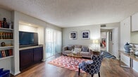 This single-floor residence offers a cohesive and functional layout designed for comfortable everyday living. The living room serves as the heart of the home, showcasing rich hardwood-style flooring, a textured ceiling, and neutral gray walls that provide a versatile backdrop. Large sliding glass doors dressed with vertical blinds fill the space with natural light and open to an outdoor patio, creating a seamless indoor-outdoor connection. A built-in media cabinet with dark cabinetry adds a practical and stylish focal point to the room.

The dining area is an intimate, dedicated nook accommodating a full dining table and seating, complete with overhead lighting — ideal for meals and gatherings. The kitchen features dark wood cabinetry, a mosaic tile backsplash, and ample counter space, with the added convenience of an in-unit washer and dryer tucked into an adjacent laundry area.

The bedroom is a quiet, carpeted retreat equipped with a ceiling fan and a generous window that invites natural light. The full bathroom includes a tub-shower combination with tiled surround, a dark wood vanity with stone countertop, and hardwood-style flooring, completing this well-rounded and move-in-ready home.