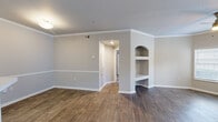 Located at 4699 Fossil Vista Dr in Haltom City, TX, this well-appointed 2-bedroom, 2-bathroom single-story home offers a thoughtfully designed layout that balances comfort and functionality. The living room is bright and welcoming, featuring crown molding, a ceiling fan, wood-look flooring, and large windows alongside a door that opens to an outdoor balcony, allowing abundant natural light to fill the space. A charming built-in arched display niche adds a distinctive architectural touch to the living area. The kitchen is equipped with white shaker-style cabinetry, light stone countertops, stainless steel appliances including a refrigerator and microwave, a subway tile backsplash, and a peninsula that provides additional prep and seating space. Both bedrooms are carpeted and include ceiling fans, natural light from windows, and dedicated closets, with one featuring a spacious walk-in closet outfitted with wire shelving. The bathrooms are finished with marble-look tile surrounds on the tub-shower combos, white vanity cabinetry, and stone countertops. Wood-look flooring flows throughout the main living areas, while a neutral color palette creates a clean, cohesive ambiance throughout the home.