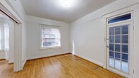 This well-appointed one-bedroom, one-bathroom residence showcases classic architectural character throughout its thoughtfully laid-out single floor. Warm hardwood flooring flows consistently through the living room, hallway, and bedroom, lending a sense of continuity and timeless charm. The living room is a standout space, highlighted by a distinctive bay window with multiple panes that invite natural light and offer pleasant outward views. A freestanding stove unit anchors the bay corner, adding a nostalgic touch to the room's character. Decorative door and wall moldings further reinforce the space's classic aesthetic. The bedroom is generously proportioned, featuring a large paneled double closet, a window overlooking neighboring brickwork, and a secondary glass-paneled door that introduces additional light. The kitchen is functional and well-equipped, featuring warm wood cabinetry, light countertops, a gas range, and a window that brightens the space. The bathroom retains a charming vintage character with a clawfoot soaking tub fitted with an overhead shower fixture, a wall-mounted sink, and clean white finishes. A connecting hallway ties all rooms together efficiently, completing this cohesive and character-rich residence.