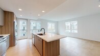 Located at 310 Del Sol Dr in San Diego, CA, this single-floor residence offers a clean, contemporary design with a cohesive open-concept layout. The kitchen is a standout feature, showcasing a large central island with a white quartz countertop, an undermount sink with a matte black faucet, and warm wood-toned cabinetry that extends to the ceiling. Stainless steel appliances — including a gas range, built-in microwave, and French door refrigerator — complement a textured tile backsplash, lending the kitchen a polished, functional character. Recessed lighting and direct access to a private balcony enhance the open living and dining area, which is bathed in natural light through oversized windows. Light-toned hardwood flooring runs throughout the main living areas and bedrooms, creating a bright and airy ambiance. The bedrooms are well-proportioned, each featuring large windows with views of the surrounding community and palm-lined grounds. The primary bathroom includes a dual-sink vanity with a wide wall mirror, taupe cabinetry, and generous counter space, while the secondary bathroom features a backlit mirror, single-sink vanity, and tiled flooring. The overall aesthetic is modern and understated, with crisp white walls, clean lines, and thoughtful finishes throughout.