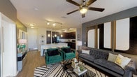 This well-appointed single-story residence in Houston, TX offers a thoughtfully designed open-concept layout that seamlessly connects the living, dining, and kitchen areas. The living room features wood-style flooring, a ceiling fan, and a bold accent wall, creating a contemporary and inviting atmosphere with ample natural light from large windows.

The kitchen is equipped with dark espresso cabinetry, granite-style countertops, black appliances including a French door refrigerator and range, a tile backsplash, track lighting, and a peninsula with bar seating — ideal for both cooking and casual dining. A dedicated in-unit laundry area is conveniently accessible nearby.

The bedrooms feature plush carpeting, ceiling fans, and accent walls. One bedroom includes a spacious walk-in closet with built-in shelving, while another benefits from generous natural light and direct bathroom access. The bathrooms are finished with dark wood vanities, granite-style countertops, large mirrors, wood-style flooring, and a tiled soaking tub and shower combination. The overall aesthetic throughout is modern and cohesive, with consistent use of neutral tones accented by deep grays and rich dark wood finishes.
