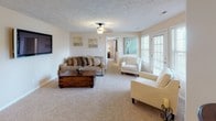 This well-appointed single-floor home offers three bedrooms and three full bathrooms, thoughtfully laid out for comfortable everyday living. The living room serves as the heart of the home, featuring plush wall-to-wall carpeting, a ceiling fan, textured ceiling, and a wall-mounted flat-screen TV. Multiple windows allow natural light to fill the space, creating a bright and welcoming atmosphere. The kitchen is designed for functionality, featuring light wood cabinetry, tile flooring, a full suite of appliances, and a peninsula counter with bar seating — ideal for casual dining or entertaining. Each of the three bedrooms is carpeted and outfitted with a ceiling fan and natural light from windows with blinds. The primary bedroom includes a walk-in closet, while the additional bedrooms offer generous space and built-in closet storage. All three bathrooms are finished with tile flooring, wood vanity cabinetry, and shower-tub combinations with curtains. The home's neutral color palette throughout creates a cohesive and calming ambiance, making it a versatile and move-in ready space.
