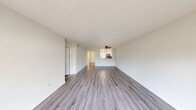 This single-story unit offers a thoughtfully designed layout with two bedrooms and two full bathrooms. The open living room is a central highlight, featuring light grey wood-look flooring, a ceiling fan, and a textured ceiling. A large sliding glass door fills the space with natural light and provides outdoor views, creating a bright and airy atmosphere. The kitchen connects seamlessly to the living area via a pass-through window and is equipped with stainless steel appliances, including a range, microwave, and refrigerator, complemented by white cabinetry, a tile backsplash, and ample counter space.

The primary bedroom features rich, dark hardwood flooring and direct access to a dedicated closet and a private en-suite bathroom. The second bedroom is finished with light wood-look flooring and benefits from dual windows that invite generous natural light. Both bathrooms are cleanly appointed with white vanities, tiled tub-shower combinations, and bright, neutral finishes. A hallway connects the bedrooms and bathrooms, contributing to an efficient and practical flow throughout the unit.