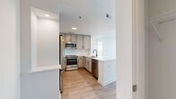 Located in the heart of Buckhead at 3242 Peachtree Rd NE, this one-bedroom, one-bathroom residence offers a thoughtfully designed open-concept layout with contemporary finishes throughout. Light wood-tone flooring runs through the main living areas, complementing the bright, neutral palette of white walls and clean architectural lines.

The kitchen is well-appointed with grey shaker-style cabinetry, white quartz countertops, a white subway tile backsplash, and a full suite of stainless steel appliances including a French door refrigerator, range, microwave, and dishwasher. An adjacent peninsula provides additional counter space and enhances flow into the living area.

The living room is bathed in natural light from expansive floor-to-ceiling windows with roller shades, opening to a balcony with striking views of the Atlanta skyline. A ceiling fan adds to the comfort of the space.

The bedroom, carpeted for warmth and comfort, features a dramatic corner configuration of floor-to-ceiling windows offering panoramic city and treetop views, along with a ceiling fan and access to a dedicated closet.

The bathroom is finished with large-format tile flooring, a vanity with grey cabinetry, a glass-enclosed shower, and a tall window that brings in abundant natural light while maintaining privacy.