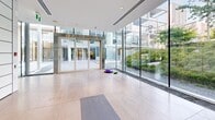 Located at 1770 Pendrell St in Vancouver's West End, this contemporary fitness facility offers a well-appointed exercise room and an adjoining patio area. The exercise room is thoughtfully designed with a clean, modern aesthetic, featuring large floor-to-ceiling windows that flood the space with natural light and offer views of the surrounding greenery. Dark rubber flooring provides a durable, professional-grade workout surface throughout the main gym area. The room is equipped with a comprehensive selection of cardio machines, including treadmills and ellipticals, alongside a full dumbbell rack and various strength training stations and benches. A wall of mirrors enhances the sense of space and supports proper form during workouts. Adjacent to the main gym floor is a dedicated stretch and yoga area, finished with large-format light stone tiles and mirrored walls, offering a calm and open environment for flexibility training and mat exercises. Sliding partition doors connect the two zones, allowing for flexible use of the space. Floor-to-ceiling glass walls in the stretch area provide direct views onto a landscaped outdoor patio, seamlessly blending indoor and outdoor wellness. The overall ambiance is bright, polished, and professionally curated, reflecting a high standard of amenity design.