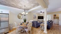 Located at 1198 Waxwing Dr in Florence, SC, this two-story, three-bedroom, three-bathroom home offers a thoughtfully designed layout spread across two floors. The main floor serves as the heart of the home, where a combined dining and living area immediately captures attention with its striking ornate tin ceiling — an elegant architectural detail that adds character and charm throughout. White decorative columns subtly separate the dining space from the living area, both of which feature warm hardwood-style flooring. The kitchen continues the refined aesthetic with white shaker cabinetry, dark granite countertops, a classic tile backsplash, and stainless steel appliances, all beneath a matching embossed tin ceiling.

The primary bedroom is generously sized, showcasing a coffered tray ceiling with crown molding, hardwood-style floors, a ceiling fan, and direct access to a walk-in closet. Its en-suite bathroom features granite countertops and a tiled shower. Additional bedrooms are well-proportioned, each offering ceiling fans and ample natural light. The bathrooms throughout maintain a consistent finish with granite vanity tops and clean tile work. A staircase leads to the upper floor, which provides additional flexible living space. The home's cohesive design and quality finishes make it a distinctive residence in Florence.