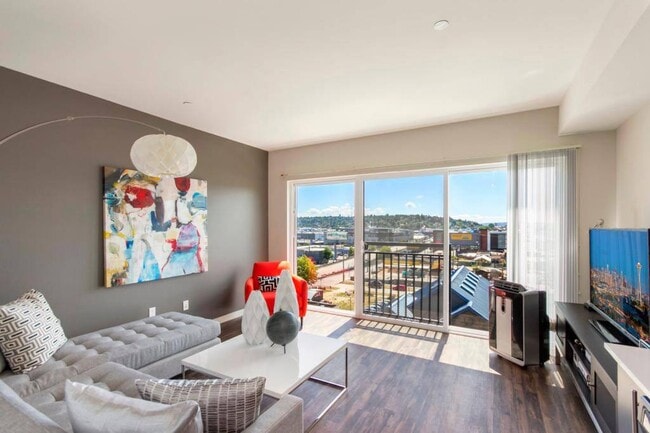 A spacious living room with large windows and a sliding glass door leadnig out to the Juliet balcony - Vive