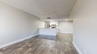 This single-floor residence offers a clean, functional layout with a neutral color palette and modern finishes throughout. The open-concept living and dining area flows seamlessly into the kitchen, which is defined by a peninsula counter, white cabinetry, and stainless steel appliances including a refrigerator and a gas range. Wood-look plank flooring runs throughout the main living areas, adding warmth and visual continuity.

The entry area features the same wood-look flooring and a window that brings in natural light, creating a welcoming first impression. The bedrooms are generously sized, each finished with plush wall-to-wall carpeting and windows fitted with blinds that allow for natural light and privacy. The textured ceilings carry through each room, adding a consistent design element across the space.

The bathrooms are well-appointed, with one featuring a wide white vanity with ample cabinet storage, dual mirrors, and wood-look flooring. A second bathroom includes a stand-alone shower unit, a toilet, and matching flooring. Both bathrooms maintain a bright, clean aesthetic with white fixtures and neutral tones. Overall, the space is designed with practicality and comfort in mind, offering a move-in ready environment with cohesive finishes throughout.
