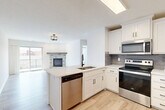 Located in Gretna, Nebraska, this well-appointed one-bedroom, one-bathroom unit offers a thoughtfully designed open-concept layout. The combined kitchen and living area serves as the heart of the home, featuring light hardwood-style flooring that flows seamlessly throughout. The kitchen is outfitted with crisp white shaker cabinetry, a gray subway tile backsplash, a quartz-topped peninsula with an undermount sink, and a full suite of stainless steel appliances including a dishwasher, electric range, microwave, and refrigerator. The living room is anchored by a striking corner fireplace clad in gray brick tile with a rustic wood mantel, and a sliding glass door opens to a private balcony, allowing abundant natural light to fill the space. The bedroom offers plush wall-to-wall carpeting, a ceiling fan, and a window with outdoor views, complemented by a dedicated closet for storage. The bathroom is finished with light wood-look flooring, white cabinetry, and matte black hardware and fixtures, with a full tub-shower combination. Clean white walls, consistent modern hardware, and a bright, neutral palette unify the space and create a fresh, contemporary ambiance throughout.