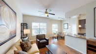 This single-story, two-bedroom, two-bathroom Phase 1 unit offers a well-designed, open-concept layout that seamlessly connects the living, dining, and kitchen areas. The living room features warm hardwood-style flooring, a ceiling fan, and multiple windows fitted with blinds that allow generous natural light to fill the space. The kitchen is equipped with dark espresso cabinetry, granite countertops, stainless steel appliances including a microwave, electric range, and refrigerator, along with a peninsula that provides additional seating and prep space. A pendant light and track lighting illuminate the kitchen, while a dedicated dining area nearby accommodates a full dining table set beneath another window with outdoor views.

Both bedrooms are carpeted and generously sized, each featuring ceiling fans and multiple windows for natural light. The primary bedroom includes a walk-in closet with built-in shelving. The two bathrooms are finished with dark wood vanities, granite countertops, and tile flooring. One bathroom offers a soaking tub with tiled surround, while the second features a glass-enclosed walk-in shower. The overall ambiance is clean, neutral, and inviting throughout.