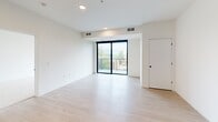 Located at 255 Western Ave N in Saint Paul, Minnesota, this single-floor residence showcases a clean, modern aesthetic with a thoughtfully designed open layout. The kitchen is a standout feature, equipped with stainless steel appliances including a range, microwave, and dishwasher, complemented by white cabinetry with matte black hardware, dark countertops, a white subway tile backsplash, and a matte black faucet at the undermount sink. A central island with a dark countertop provides additional workspace and casual seating. Light wood-tone flooring flows throughout the main living areas, enhancing the bright, airy atmosphere created by white walls and recessed lighting. The spacious living area opens directly to a private balcony through sliding glass doors, offering pleasant outdoor views of the surrounding neighborhood's mature trees and green space. The bedrooms feature plush carpeting and large black-framed windows that fill each room with natural light and frame views of the greenery outside. The bathroom is finished in a crisp, minimalist style with a wide vanity, white cabinetry, a large mirror, and a full tub-shower combination. Additional flexible spaces with wood-tone flooring provide versatile options for a home office or den, completing this well-appointed and contemporary residence.