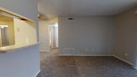 Located at 2609 Featherstone Rd in Oklahoma City, Oklahoma, this single-floor residence offers a practical and comfortable layout with a neutral color palette throughout. The spacious living area is finished with plush carpeting and features textured ceilings, painted gray walls, and a half-wall partition that separates it from the kitchen. HVAC vents are conveniently positioned for climate control, and the room flows naturally toward a hallway leading to the rest of the unit. A separate room with large windows dressed in horizontal blinds allows ample natural light to fill the space, making it feel bright and welcoming. Another carpeted room features floor-to-ceiling vertical blinds covering a wide sliding door, providing privacy and light control. The galley-style kitchen is equipped with light wood cabinetry, a double-basin sink, a coil-burner electric range, a full-size refrigerator, and a dishwasher, all set above light-toned laminate wood flooring with generous counter space on both sides. The bathroom includes a white vanity with cabinet storage, a wall mirror, a toilet, and a full tub-shower combination, complemented by wood-look flooring. Overall, the space presents a clean, move-in ready environment with functional finishes throughout.