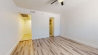 This well-maintained single-floor space offers a bright and clean aesthetic throughout, characterized by crisp white walls, light wood-style laminate flooring, and white baseboards that create a cohesive, modern feel.

The main living area is open and airy, bathed in natural light from a sizable window fitted with blinds. A ceiling fan with a built-in light fixture provides both comfort and additional illumination. The room is outfitted with multiple electrical outlets and switch panels, offering practical convenience.

The bedroom area extends into a walk-in closet, providing generous storage space. The layout flows naturally, with easy access between the main room and adjoining spaces.

The bathroom is finished with large-format neutral ceramic tile flooring and features a white vanity with a stone-look countertop and undermount sink, complemented by matte black hardware and a matching arched mirror. A built-in shelving nook adds extra storage, while clean white walls and crisp fixtures maintain a polished look throughout.

The kitchen is compact yet functional, equipped with a retro-style mint green refrigerator paired with a stainless electric coil range. White cabinetry overhead and light tile flooring complete the space. Together, these areas create a tidy, move-in-ready environment with a refreshed, contemporary character.