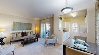 Located at 455 Dennery Rd in San Diego, CA, this single-story residence offers a well-organized floor plan designed for comfortable everyday living. The open-concept living and dining area is finished with plush carpeting and crown molding, creating a clean, polished aesthetic throughout. A pendant light fixture anchors the dining space, while the living room benefits from sliding glass doors that open onto a private balcony, filling the room with natural light and providing access to outdoor seating.

The galley-style kitchen is efficiently laid out with white cabinetry extending to the ceiling, light tile flooring, and a full suite of white appliances including a gas range, built-in microwave, and refrigerator. A charming arched window brings in additional natural light, complementing the kitchen's warm yellow accent walls.

The bedrooms are carpeted and generously proportioned. The primary bedroom features large windows with outdoor views, a mirrored sliding-door closet, and ample space for substantial furnishings. A secondary bedroom also includes good natural light, a built-in desk area, and easy access to the main living spaces.

Throughout the residence, neutral tones, crown molding details, and consistent flooring create a cohesive and inviting ambiance suited to a variety of lifestyles.