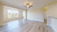 Located at 14214 Castle Top Ct in Fountain Inn, South Carolina, this single-story home offers a well-designed, functional layout with consistent finishes throughout. The galley-style kitchen is a standout feature, equipped with rich cherry wood cabinetry, granite countertops, a stainless steel sink, and a full suite of stainless steel appliances including a refrigerator, electric range, built-in microwave, and dishwasher. Light tile flooring runs through the kitchen and connects seamlessly to an adjacent dining area, which is accented by crown molding, a chair rail, and an elegant chandelier. The living spaces feature light wood-look flooring that lends a clean, modern aesthetic, complemented by warm neutral wall tones and white trim throughout. Bedrooms are generously proportioned, with large windows that invite abundant natural light and offer views of the surrounding greenery. Crown molding details add a polished finish to the primary rooms. The bathroom features tile flooring, a cherry wood vanity with granite countertop, and a full tub-shower combination. A dedicated laundry area with utility access adds everyday convenience. The overall ambiance is bright, clean, and move-in ready, reflecting a practical yet refined design suited for comfortable single-floor living.