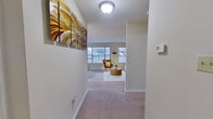 This single-floor, 2-bedroom, 2-bathroom residence offers a thoughtfully arranged layout that maximizes functionality and comfort. An entry hallway, accented by neutral-toned carpet and warm overhead lighting, leads into the open living area bathed in natural light from multiple windows with classic white blinds. The living room provides a welcoming, airy atmosphere with plush carpeting and ample space for relaxed seating arrangements. Adjacent to the living area, the dining space features a cozy corner nook illuminated by a large window, with a convenient pass-through opening to the kitchen. The kitchen is equipped with warm honey-toned wood cabinetry, granite-style countertops, tile flooring, and white appliances including a range with an overhead microwave. The primary bedroom is a comfortable retreat, featuring ceiling fan lighting, carpeted floors, and a window allowing natural light. It connects to a dedicated closet with built-in wire shelving and hanging rods. The second bedroom is equally well-appointed with ceiling fan lighting and soft carpeting. Both bathrooms include granite-topped wood vanities, tile flooring, and full tub-shower combinations with tiled surrounds. Clean, neutral tones and consistent finishes throughout create a cohesive and inviting ambiance across the entire residence.