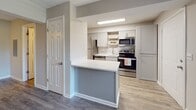 Located at 120 Azalea Hill Dr in Greenville, SC, this single-floor unit offers a clean, contemporary layout designed for comfortable everyday living. The open living area is finished with durable wood-look plank flooring and neutral gray walls, creating a bright and inviting atmosphere. A large window allows natural light to fill the space, offering views of the surrounding greenery, while a ceiling fan provides year-round comfort. The textured ceiling adds a classic touch throughout the main living areas.

The kitchen is a standout feature, thoughtfully updated with white shaker-style cabinetry, open wood shelving, and a marble-style tile backsplash. A white quartz countertop peninsula separates the kitchen from the living space, providing additional prep and serving area. Stainless steel appliances — including a refrigerator, electric range, microwave, and dishwasher — along with a deep stainless sink with a modern gooseneck faucet, complete the functional yet stylish kitchen.

The bathroom features a full tub-and-shower combination with white subway tile surround, maintaining the unit's clean and consistent aesthetic. Wood-look flooring carries through the space, tying the rooms together cohesively. Overall, this unit presents a refreshed, move-in-ready interior with modern finishes throughout.