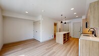 Located on the third floor at 820 N State St in Bellingham, Washington, this thoughtfully designed studio unit offers a compact yet functional single-floor layout. Light wood-tone luxury vinyl plank flooring runs throughout, creating a warm and cohesive aesthetic.

The kitchen is a standout feature, showcasing flat-panel light wood cabinetry extending to the ceiling for ample storage, paired with crisp white quartz countertops. A full suite of stainless steel appliances includes a French door refrigerator, electric range, built-in microwave, and dishwasher. A kitchen island provides additional prep space, and stylish matte black pendant lights overhead add a modern finishing touch.

The open living area benefits from an oversized picture window that floods the room with natural light and offers views of mature trees and the surrounding neighborhood streetscape, providing a pleasant and airy atmosphere.

The bathroom is clean and contemporary, featuring a wood-toned vanity with a stone-finish countertop, a full soaking tub with shower combination, and coordinating matte black fixtures and hardware throughout. White walls and light flooring keep the space feeling bright and fresh.

Overall, the unit presents a modern, minimalist design with consistent finishes and efficient use of space, making it a well-appointed residence in Bellingham's North State Street corridor.